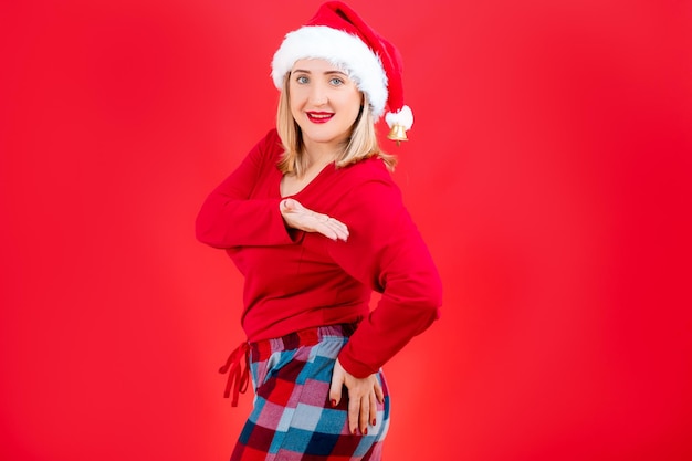 Blonde kerstpyjama staat zijwaarts met haar hand op haar heupen