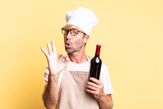 Blonde knappe chef-kok volwassen man met een fles wijn