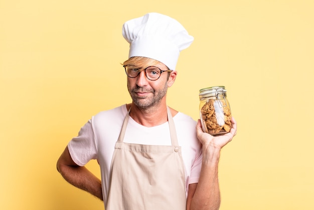 Blonde knappe chef-kok volwassen man met een fles zelfgemaakte koekjes