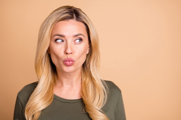 Blonde lady posing against the beige wall