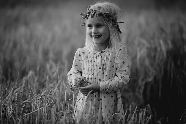 小穂を持つ野原の金髪の小さな女の子