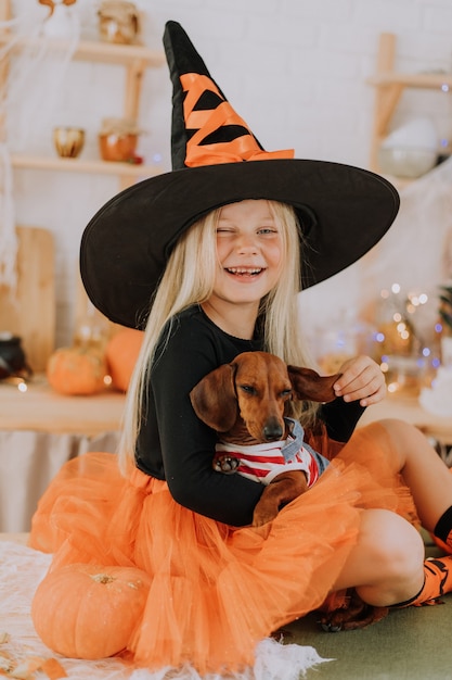 blonde little girl in a witch costume in huge witch hat and an orange puffy skirt Halloween concept