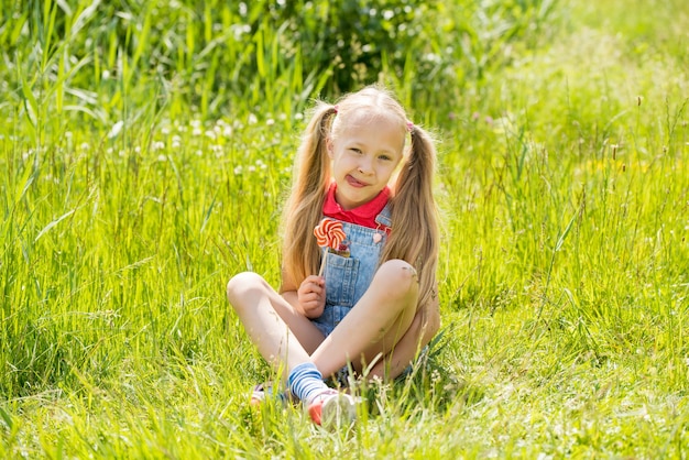 Blonde little girl with long hair and candy on a stick