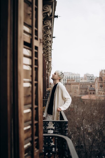 Photo blonde male standing on balcony in beautiful building