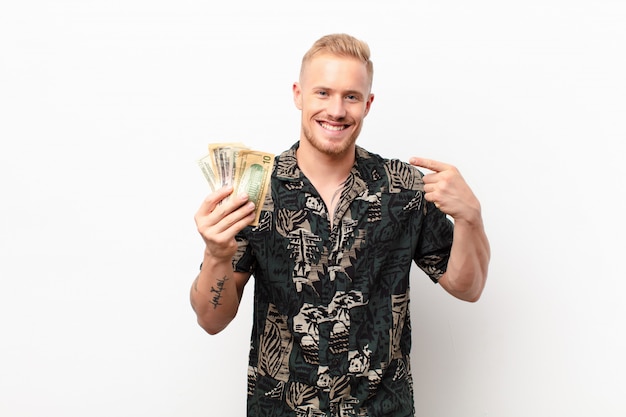 blonde man holding money and confidently pointing to own broad smile