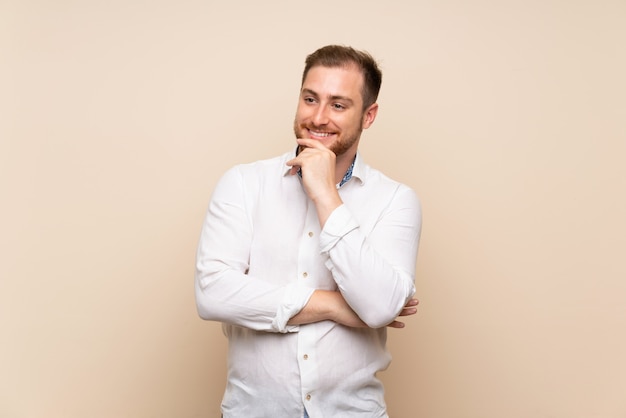 Blonde man over isolated background looking to the side