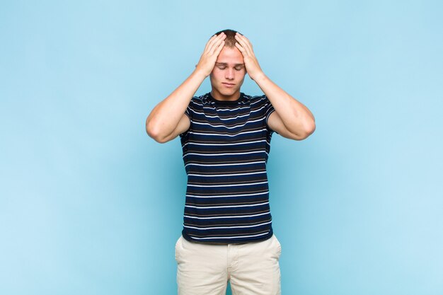 Photo blonde  man looking concentrated, thoughtful and inspired, brainstorming and imagining with hands on forehead