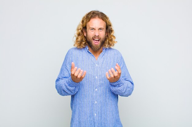 Blonde man looking desperate and frustrated, stressed, unhappy and annoyed, shouting and screaming