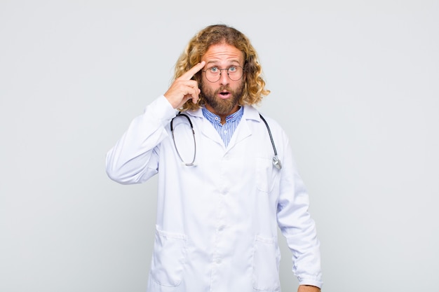 Blonde man looking surprised, open-mouthed, shocked, realizing a new thought, idea or concept