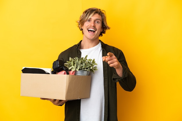 Blonde man making a move while picking up a box full of things isolated