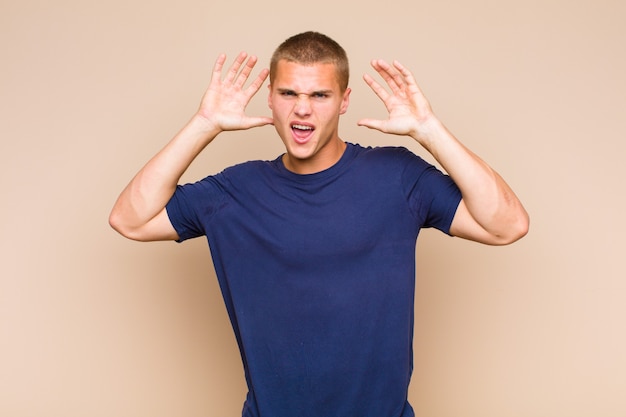 Blonde  man screaming in panic or anger, shocked, terrified or furious, with hands next to head