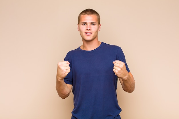 Blonde  man shouting triumphantly, laughing and feeling happy and excited while celebrating success