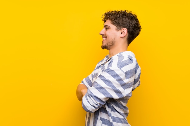 Photo blonde man over yellow wall in lateral position