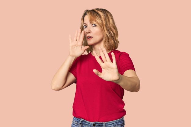 Photo blonde middleaged caucasian woman in studio being shocked due to an imminent danger