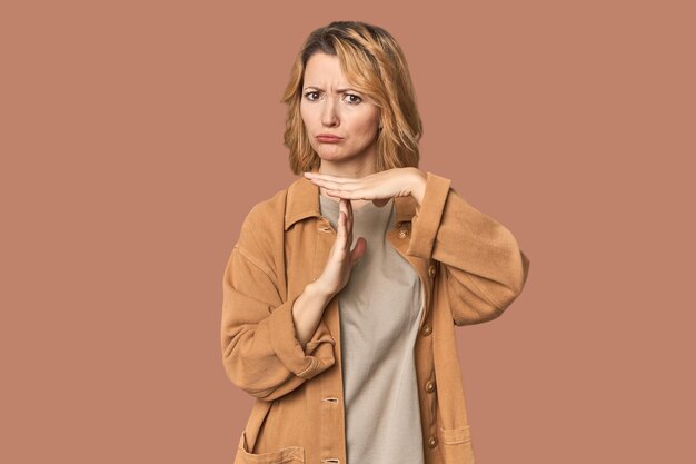 Photo blonde middleaged caucasian woman in studio showing a timeout gesture