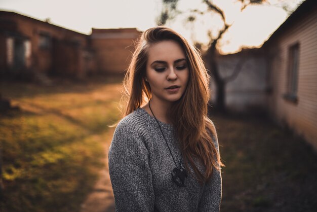 blonde model meisje in grijze gebreide trui bij zonsondergang
