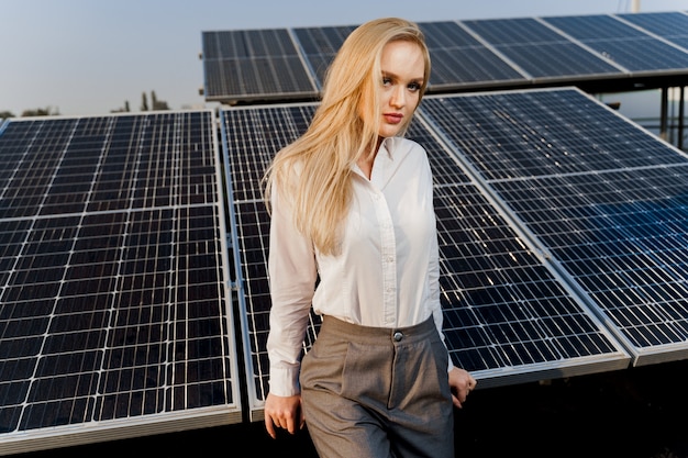 Blonde model with solar panels stands in row on the ground