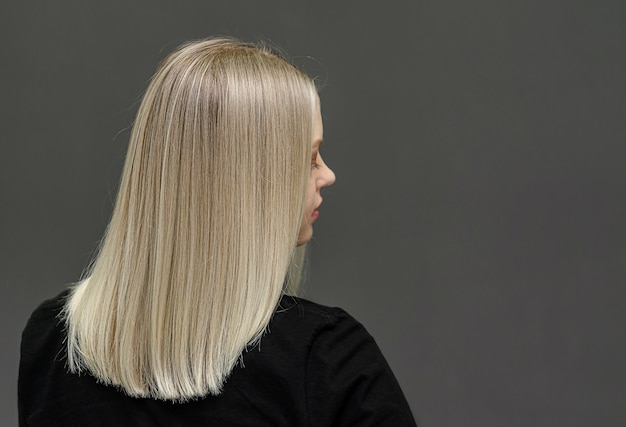 Blonde model with straight hair, look from behind. Hair bleaching result. Space for text