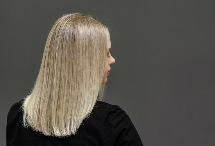 ストレートヘアの金髪モデル、後ろから見てください。ヘアブリーチの結果。テキスト用のスペース