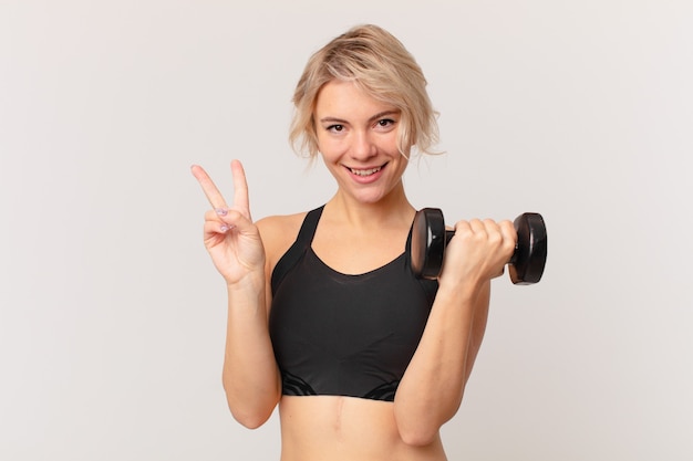 Blonde mooie vrouw die een halter opheft