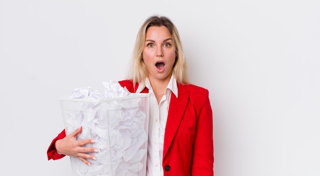 Blonde mooie vrouw die erg geschokt of verrast kijkt met het concept van fouten met papieren ballen