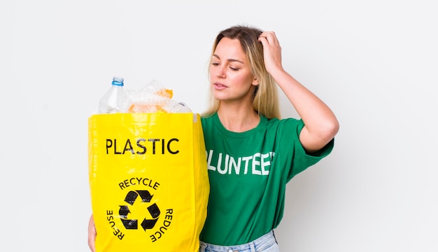 Blonde mooie vrouw die gelukkig glimlacht en dagdroomt of twijfelt aan recycleconcept