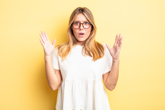 Blonde mooie vrouw die geschokt en verbaasd kijkt, met open mond van verbazing toen ze zich iets ongelooflijks realiseerde