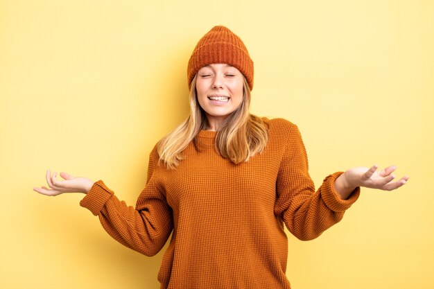 Blonde mooie vrouw die haar schouders ophaalt met een domme, gekke, verwarde, verbaasde uitdrukking, geïrriteerd en geen idee