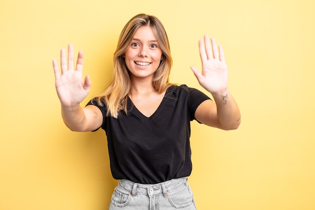 Blonde mooie vrouw die lacht en er vriendelijk uitziet, nummer tien of tiende toont met de hand naar voren, aftellend