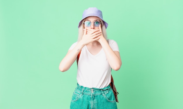 Blonde mooie vrouw die mond bedekt met handen met een geschokt. zomer concept