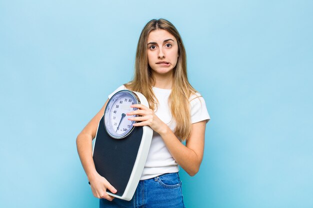 Blonde mooie vrouw die verbaasd en verward kijkt