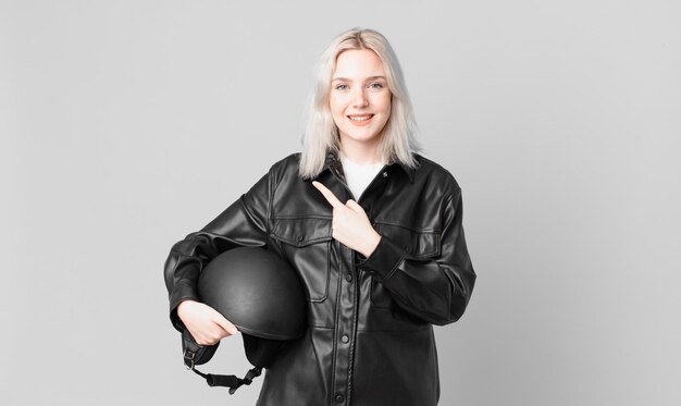 Blonde mooie vrouw die vrolijk lacht, zich gelukkig voelt en naar de zijkant wijst. motorrijder concept