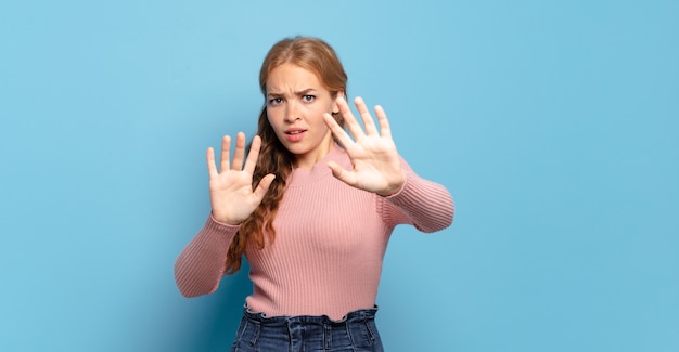 Blonde, mooie vrouw die zich doodsbang voelde, achteruitging en schreeuwde van afgrijzen en paniek, reagerend op een nachtmerrie