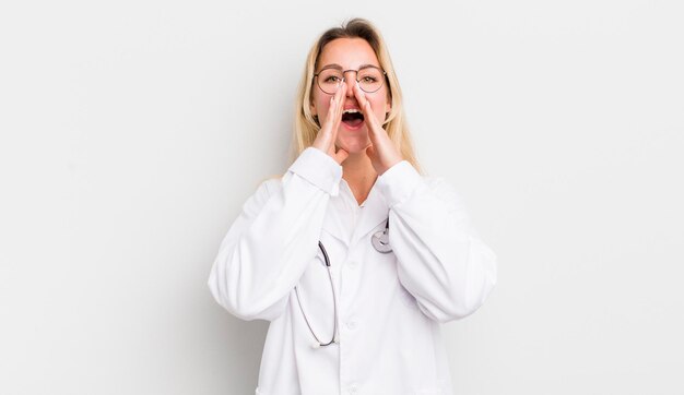 Blonde mooie vrouw die zich gelukkig voelt en een grote schreeuw geeft met de handen naast de mond