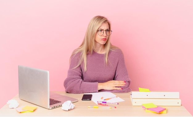 Blonde mooie vrouw jonge blonde vrouw die zich verdrietig, overstuur of boos voelt en opzij kijkt en met een laptop werkt