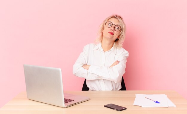 Blonde mooie vrouw jonge mooie vrouw die haar schouders ophaalt, zich verward en onzeker voelt. werkruimte bureau concept