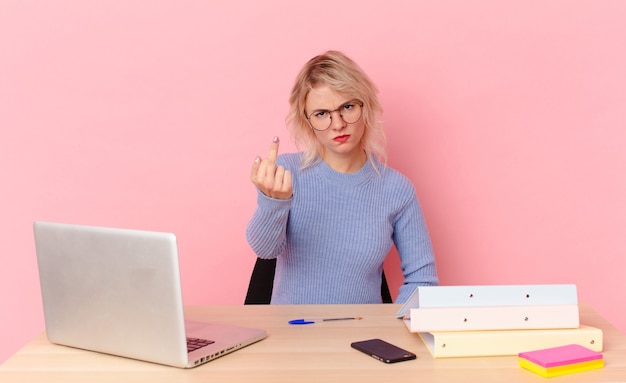 Blonde mooie vrouw jonge mooie vrouw die zich boos, geïrriteerd, opstandig en agressief voelt. werkruimte bureau concept