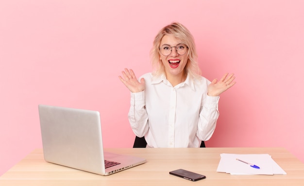 Blonde mooie vrouw jonge mooie vrouw voelt zich gelukkig en verbaasd over iets ongelooflijks. werkruimte bureau concept