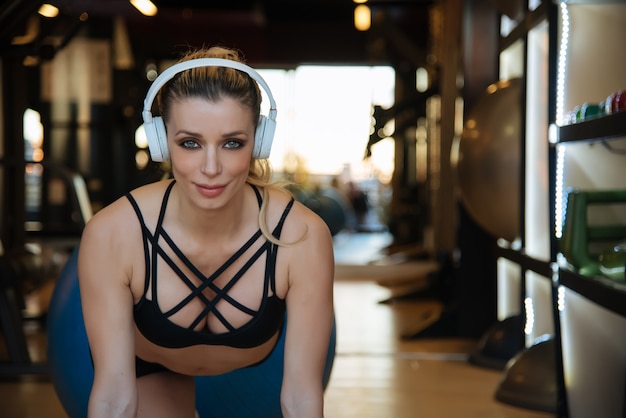 Blonde mooie vrouw opleiding in de gymnastiek het luisteren muziek