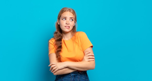 Blonde, mooie vrouw twijfelt of denkt, bijt op lip en voelt zich onzeker en nerveus, op zoek naar ruimte aan de zijkant