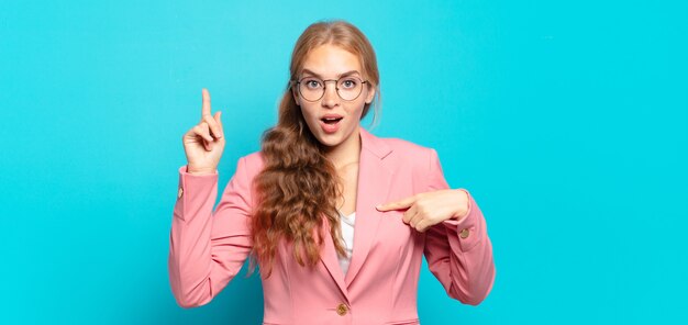 Blonde mooie vrouw voelt zich trots en verrast, wijst zelfverzekerd naar zichzelf, voelt zich succesvol nummer één