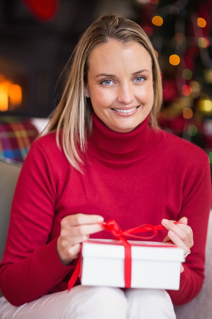 blonde opening christmas gift while smiling at camera