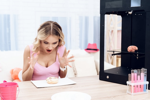 A blonde in a pink dress looks surprised at a donut.