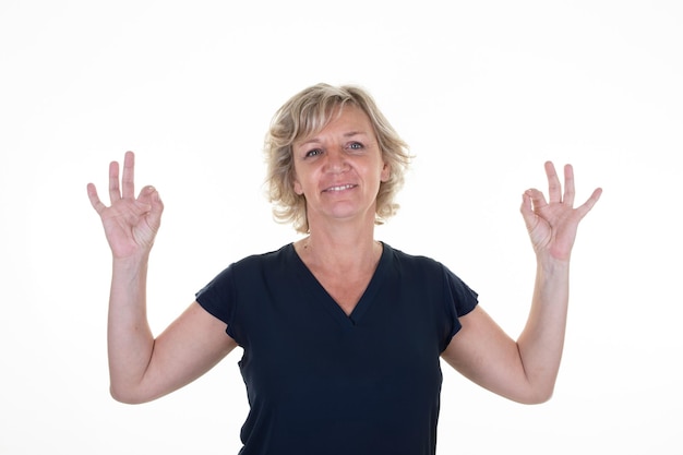 Blonde portret senior 60 mooie vrouw van middelbare leeftijd maken ok teken vingers oké hand in witte achtergrond