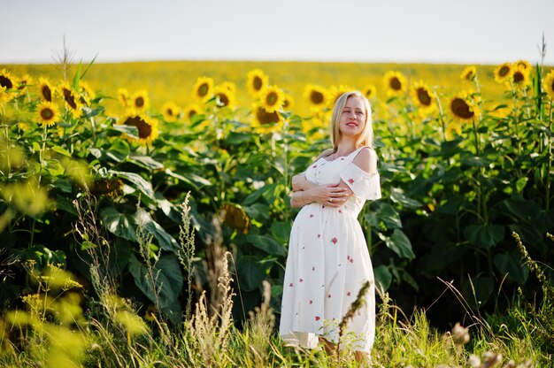 Blonde pregnant mother in sunflowers field. Moments of pregnancy