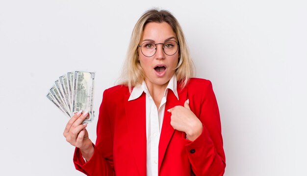 Blonde pretty woman feeling happy and pointing to self with an excited dollar banknotes concept