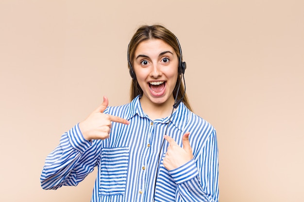 Blonde pretty woman feeling happy, surprised and proud, pointing to self with an excited, amazed look