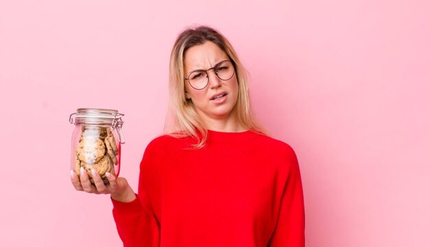 Donna graziosa bionda che si sente perplessa e confusa concetto di biscotti