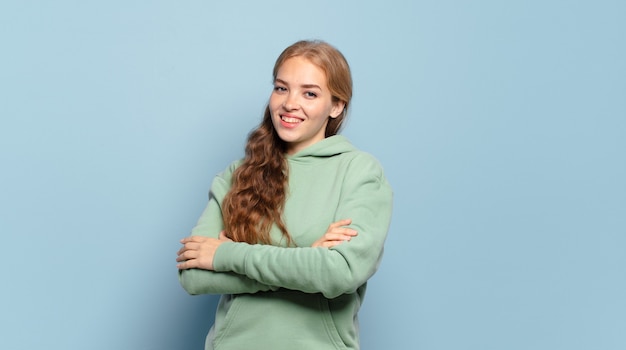 Blonde pretty woman laughing happily with arms crossed, with a relaxed, positive and satisfied pose