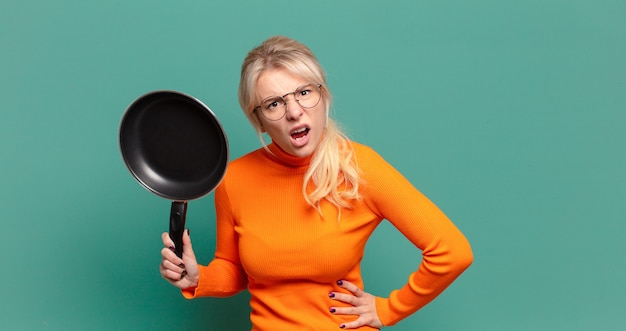 Blonde pretty woman learning cook with a pan